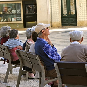 Older men and women sitting on a seat in a piazza