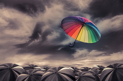 Change Concept Colorful umbrella flying over black umbrellas