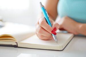 woman writes bucket list in blank diary