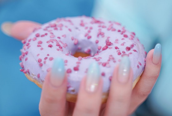 Woman holding iced donut