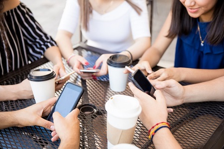 Group of Gen Z friends with phones and coffee