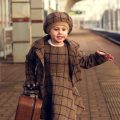 Confident young girl with suitcase at station