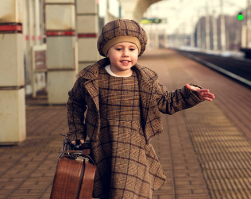 Confident young girl with suitcase at station