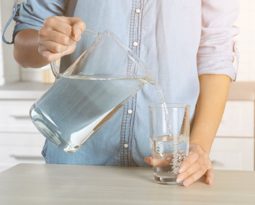 woman pouring water from jug to glass